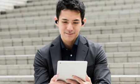Student with earphones interacts with a tablet device